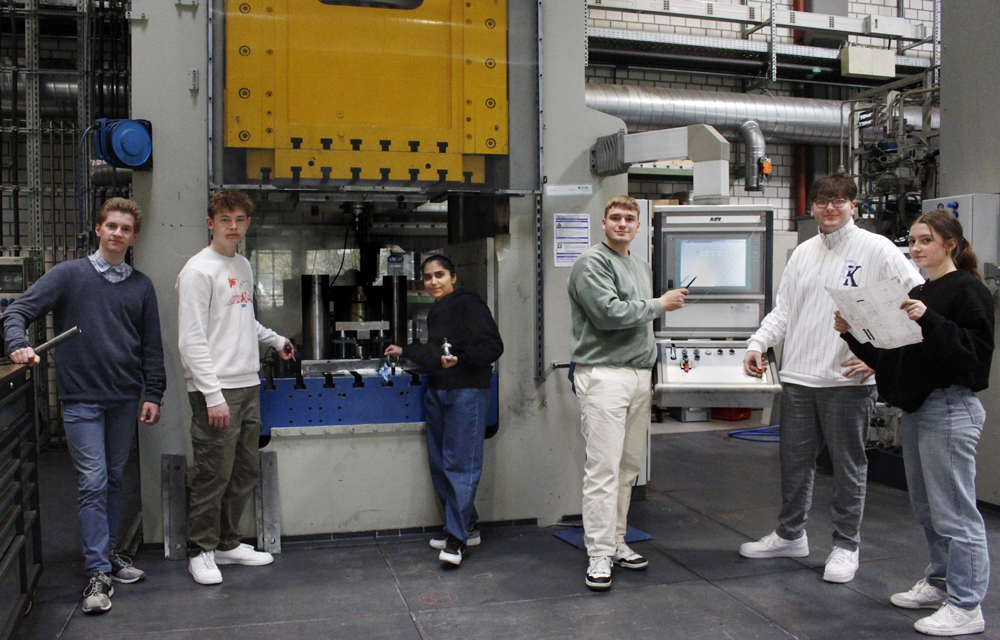 6 junge Menschen stehen vor einer Maschine