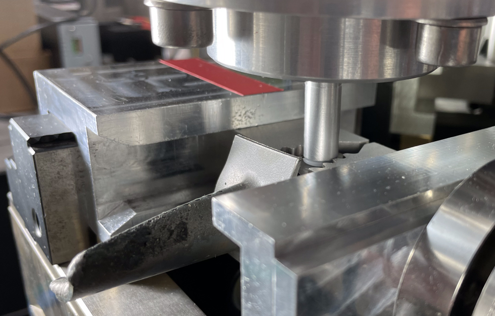 Eine Nahaufnahme eines metallverarbeitenden Fertigungsprozesses. Ein Fräswerkzeug bearbeitet präzise ein Metallteil auf einer CNC-Maschine. Die glänzende Metalloberfläche und die Präzision der Bearbeitung sind deutlich sichtbar.